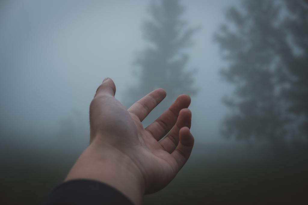 A hand reaching up into mist.